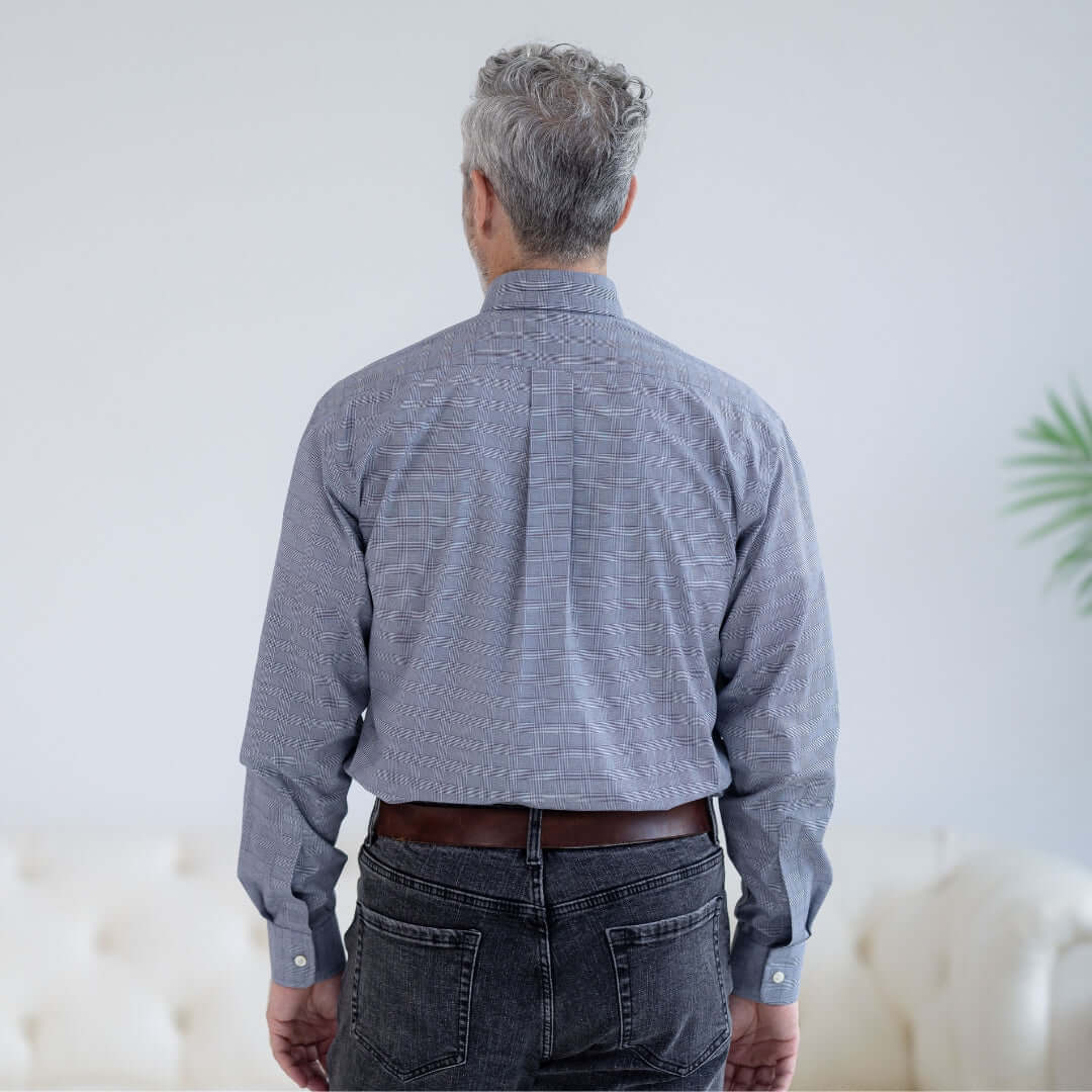 Back view of a man wearing a stretch long sleeve navy plaid button-down shirt with magnetic closures.