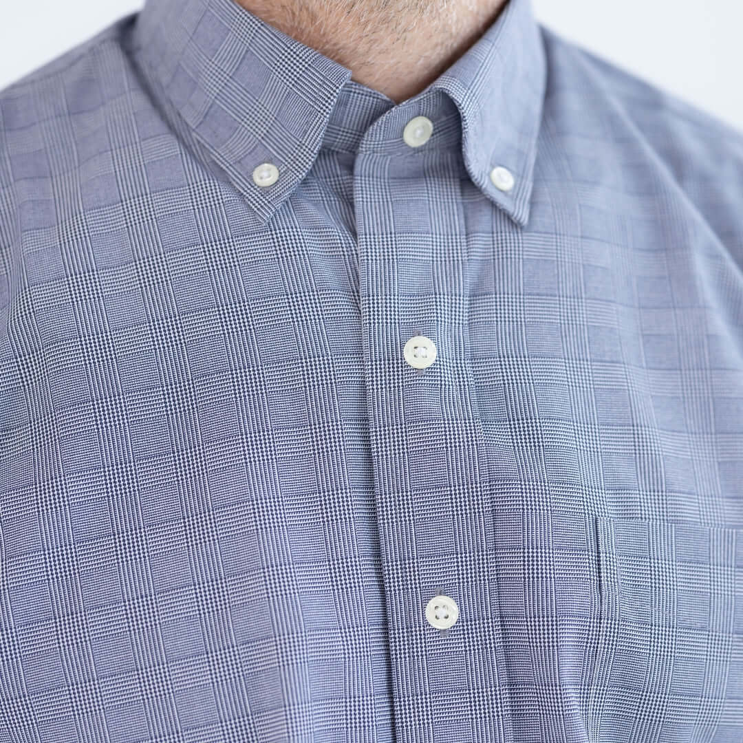 Close-up of a navy plaid button-down shirt with collar and button closures, designed for adaptive wear.