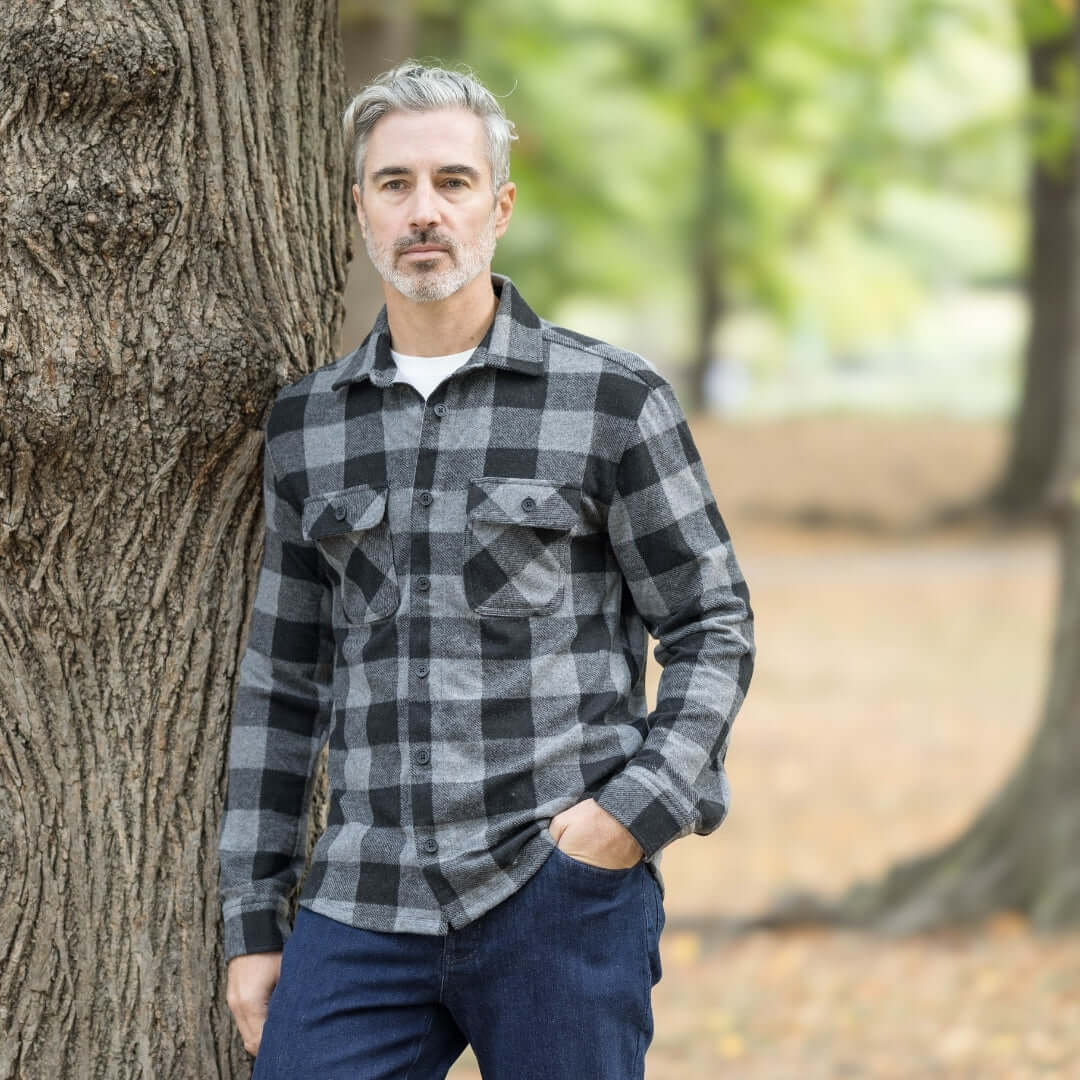 Man wearing a black buffalo check flannel shirt in a park, showcasing a stylish fall look.