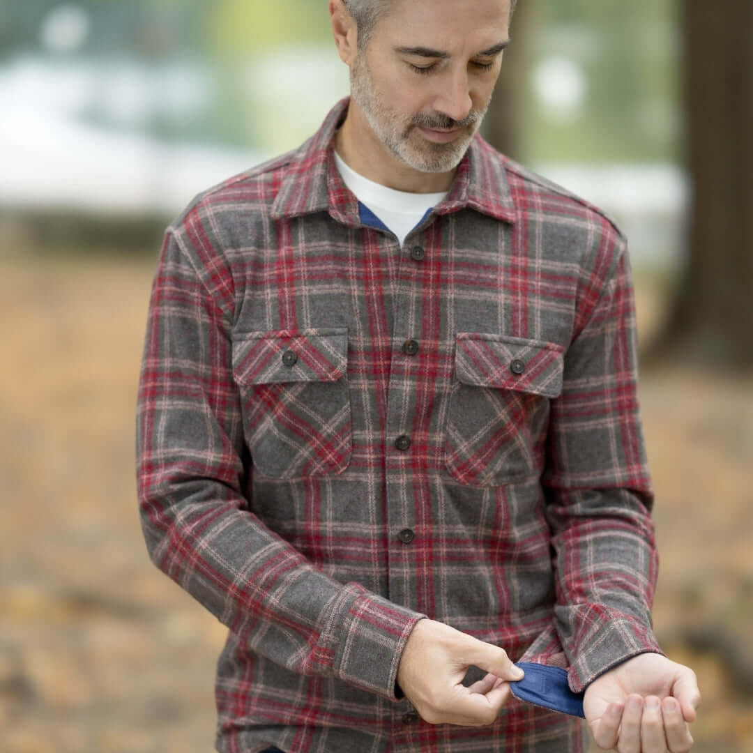 Man wearing an adaptive brown glen plaid flannel shirt with magnetic closures in an outdoor setting.