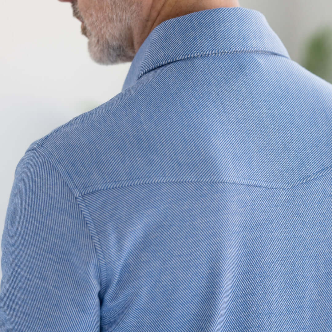Back view of a man wearing a stylish blue knit twill shirt with a Western collar.
