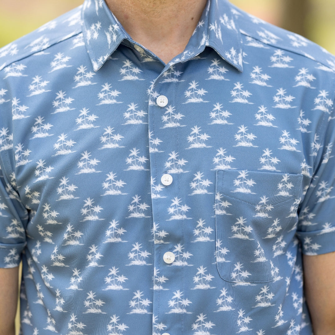 Adaptive Cooling Magnetic Front Short Sleeve Shirt in Blue Palm displayed outdoors with palm print design.