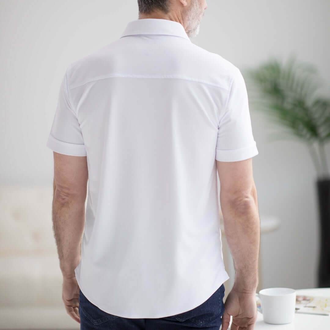 Back view of a man wearing a white adaptive cooling magnetic short sleeve polo shirt.