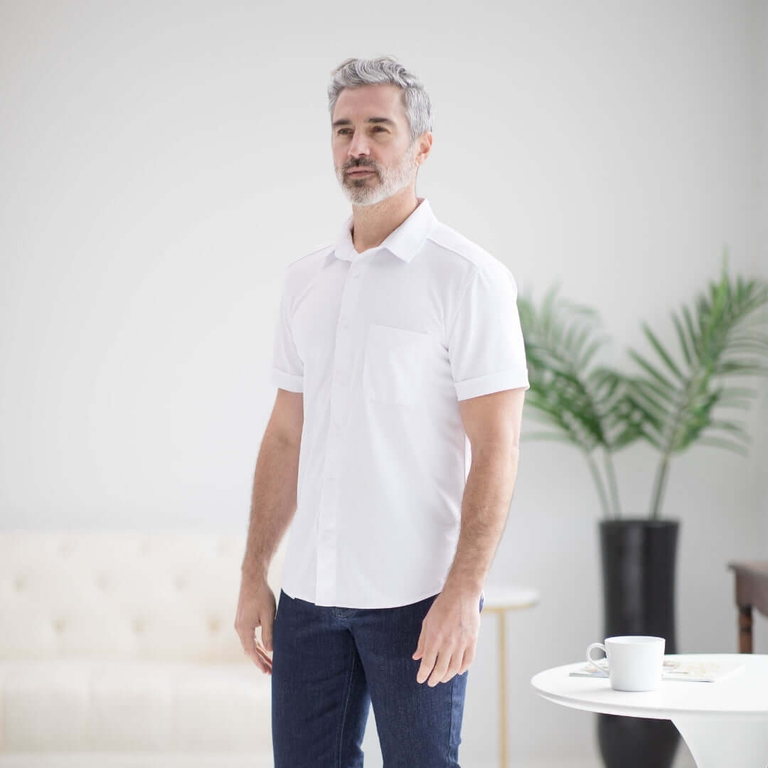 Man wearing a white adaptive cooling magnetic front short sleeve polo shirt for comfort and mobility support.