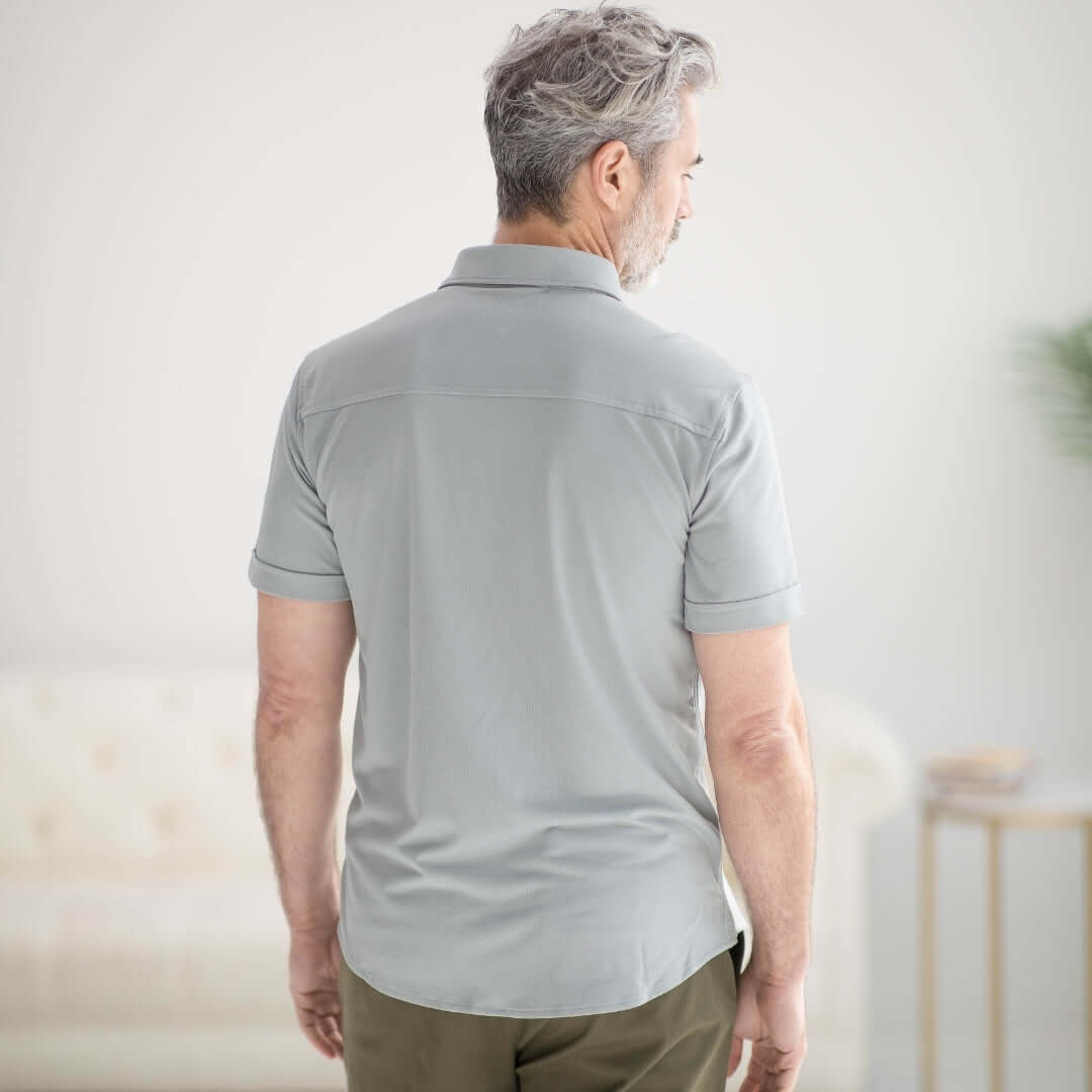 Back view of a man wearing a grey adaptive cooling magnetic shirt designed for comfort and mobility.