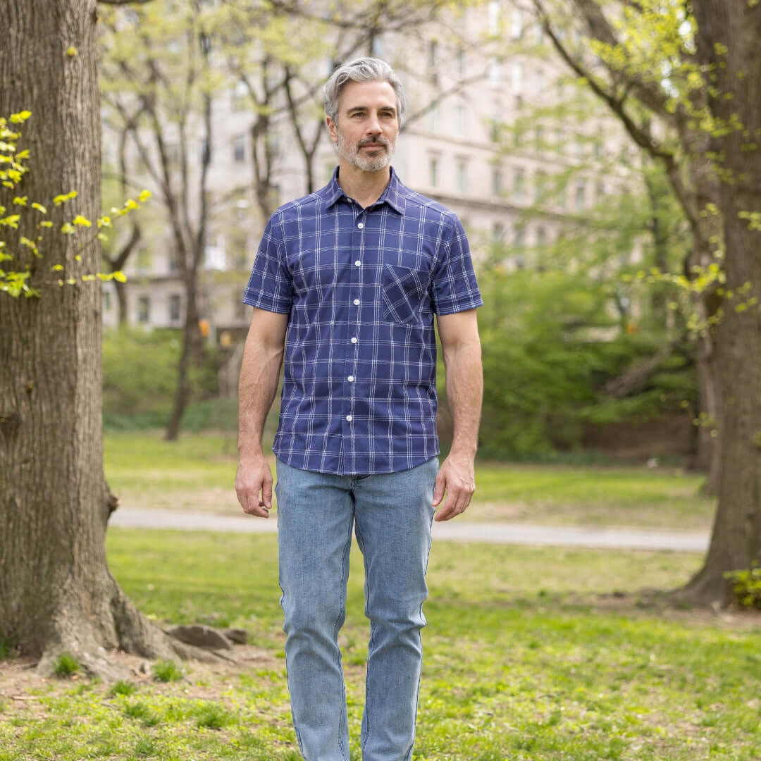 Adaptive Cooling Magnetic Front Short Sleeve Shirt in Navy Windowpane worn by a man outdoors in a park.