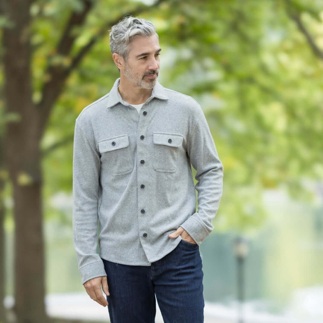 Man wearing an adaptive grey flannel shirt with pockets in a park setting, showcasing a stylish and versatile look.