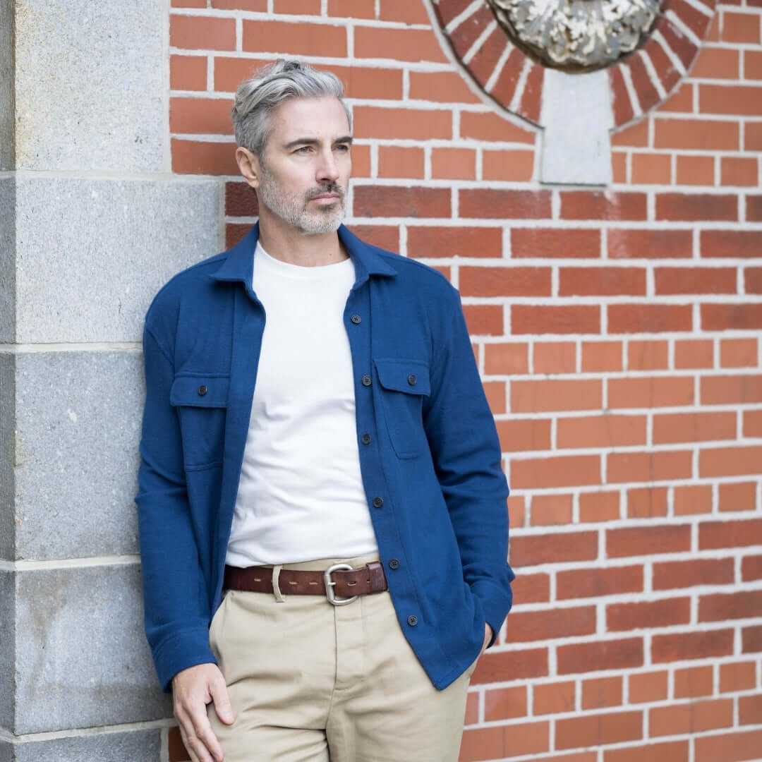 Man wearing an adaptive indigo flannel shirt against a brick wall, showcasing a stylish and versatile look.
