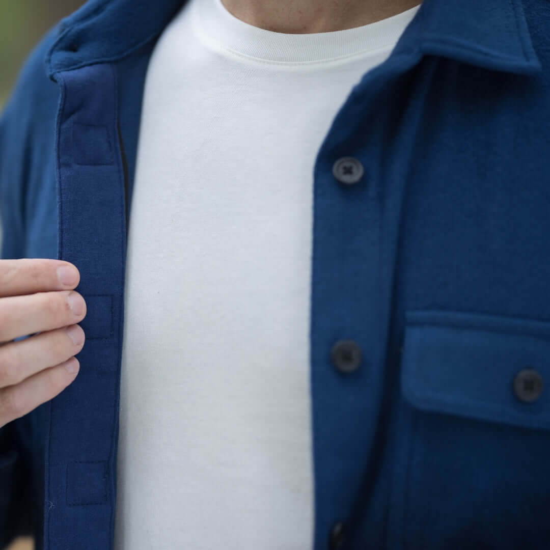 Close-up of a man wearing an adaptive indigo flannel shirt with magnetic closures over a white t-shirt.