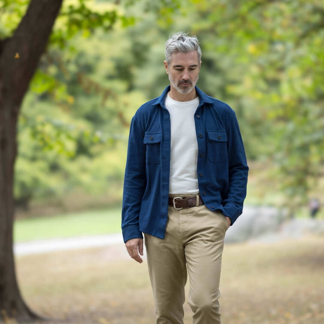 Man walking outdoors in a blue adaptive flannel shirt, styled as a jacket, paired with beige pants.