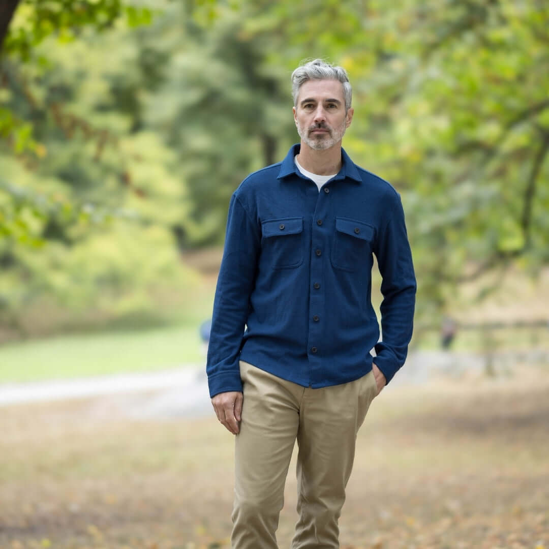 Man in a blue adaptive flannel shirt layered in a park, perfect for seasonal fashion and comfort.