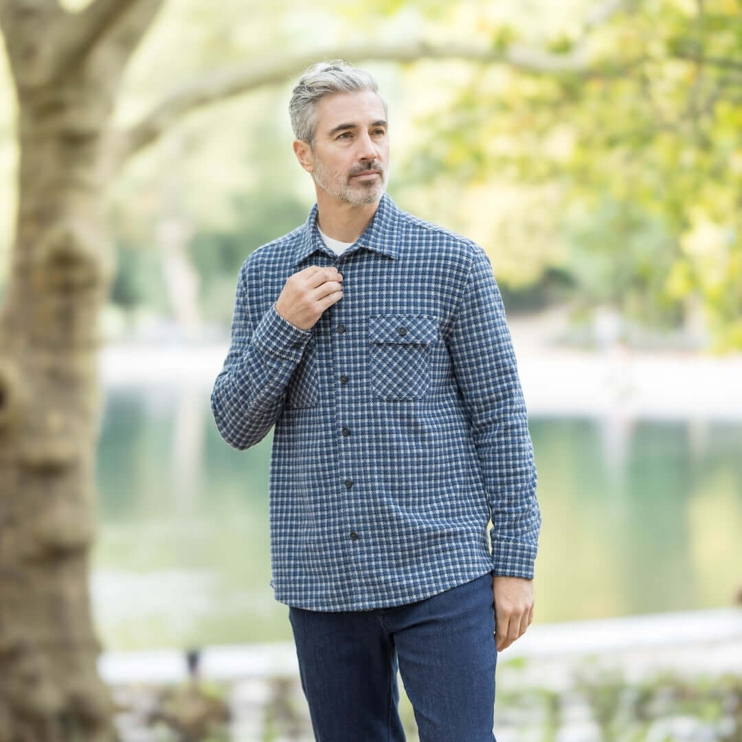 Man wearing an adaptive white and navy check flannel shirt outdoors by a lake, showcasing style and versatility.