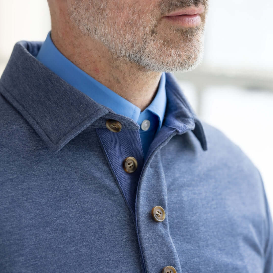 Close-up of a man wearing a heathered navy adaptive magnetic sweatshirt with a collared shirt underneath.