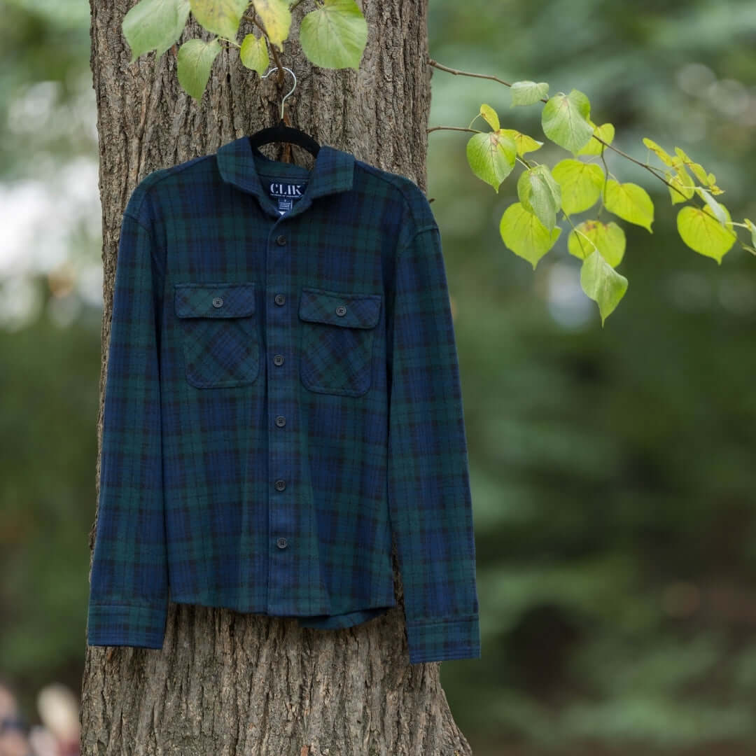 Adaptive navy and green check flannel shirt displayed on a tree, perfect for layering in changing seasons.