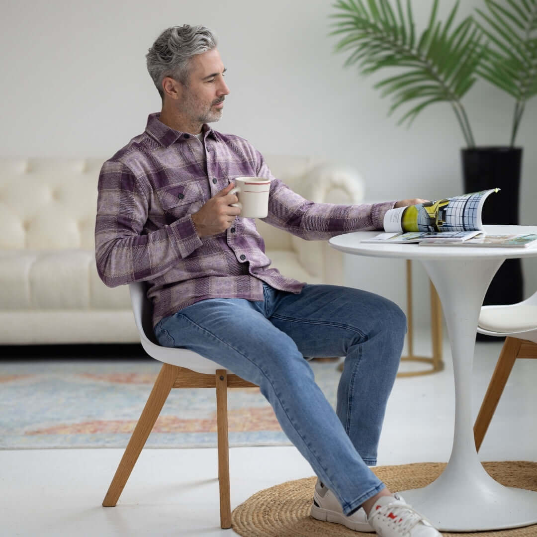 Man sitting at a table wearing an Adaptive Orchid Plaid Flannel Shirt with Magnetic Closures, enjoying a cup of coffee.