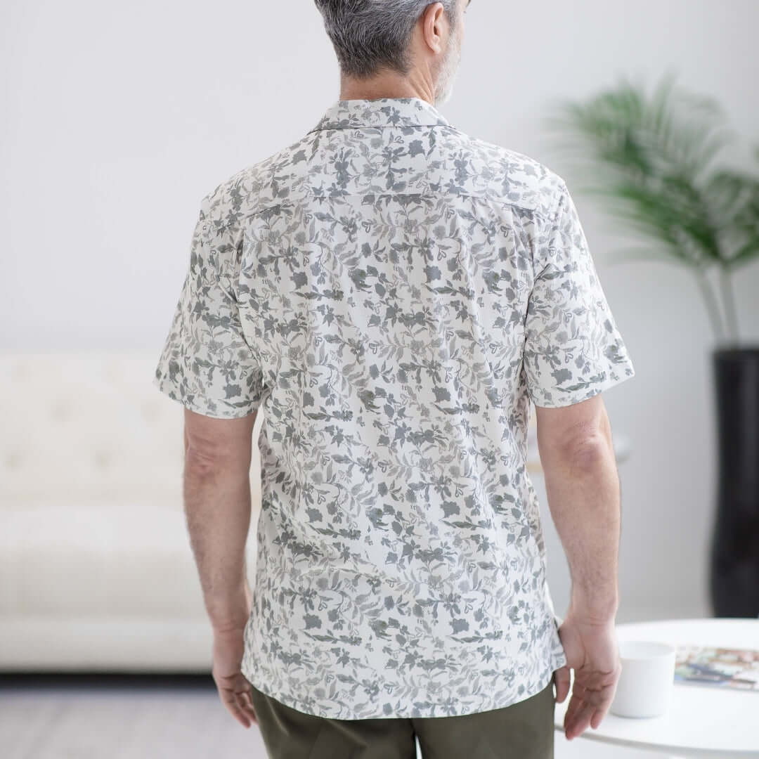 Back view of a man wearing a grey floral untucked short sleeve cooling shirt designed for comfort and accessibility.