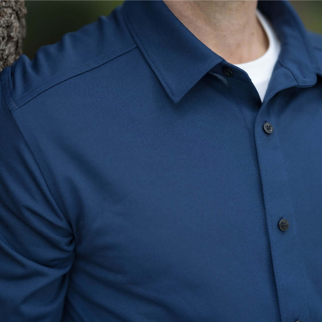 Close-up of a man wearing an adaptive true navy long sleeve polo shirt with magnetic buttons.
