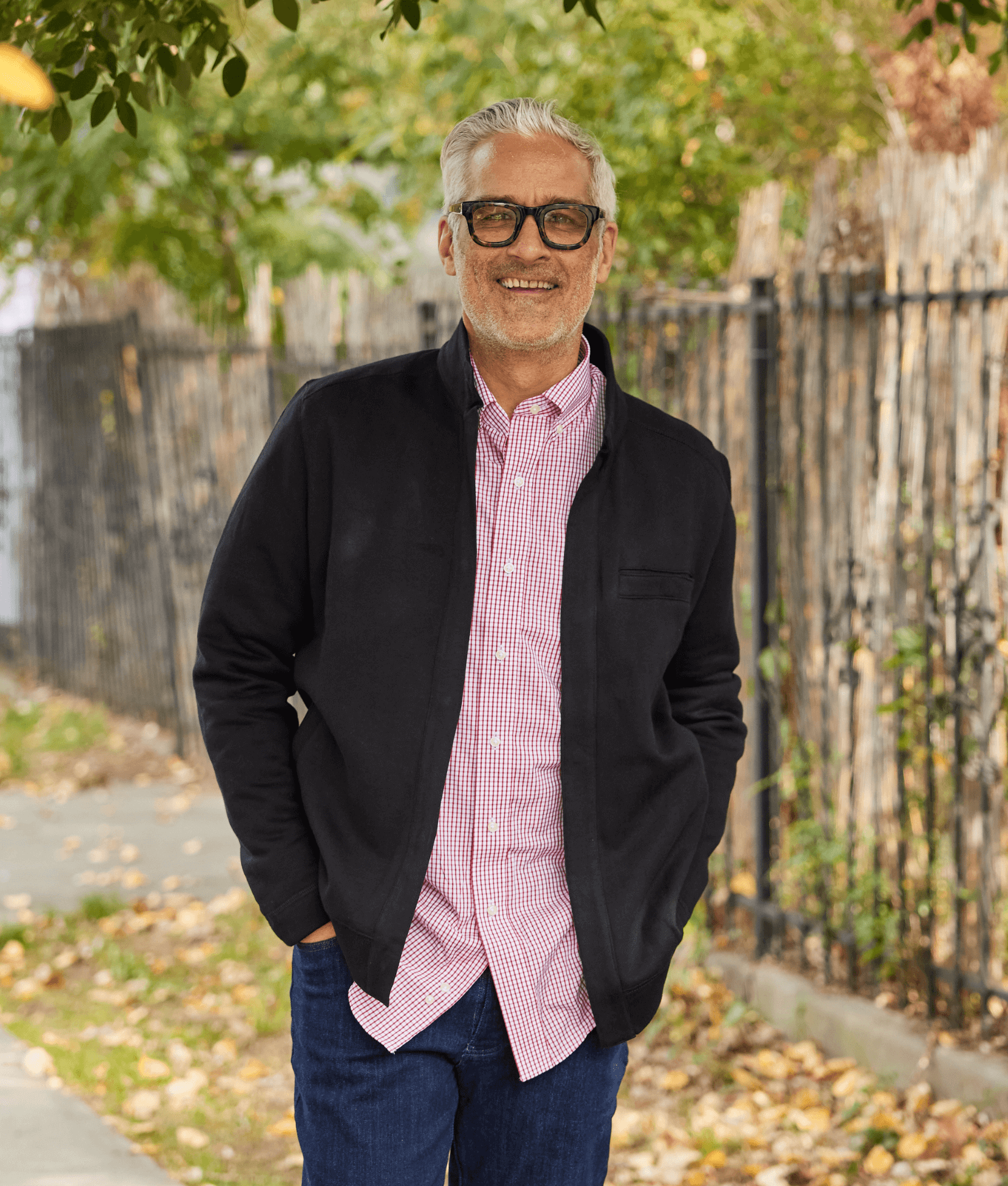 Man wearing a black knit fleece long sleeve Dillon jacket with magnetic closures, smiling outdoors.