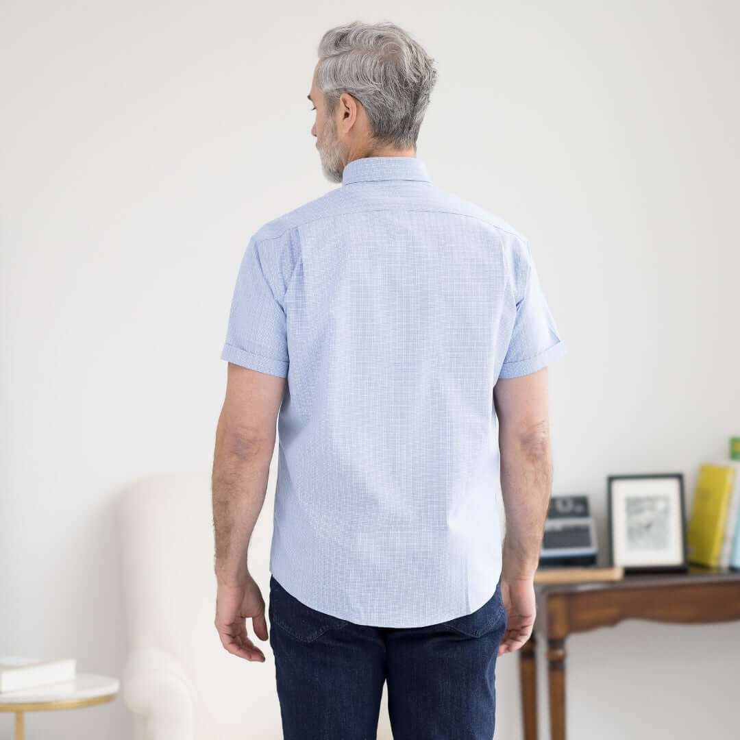 Back view of a man wearing a blue check short sleeve button-down collar shirt with magnetic closures.