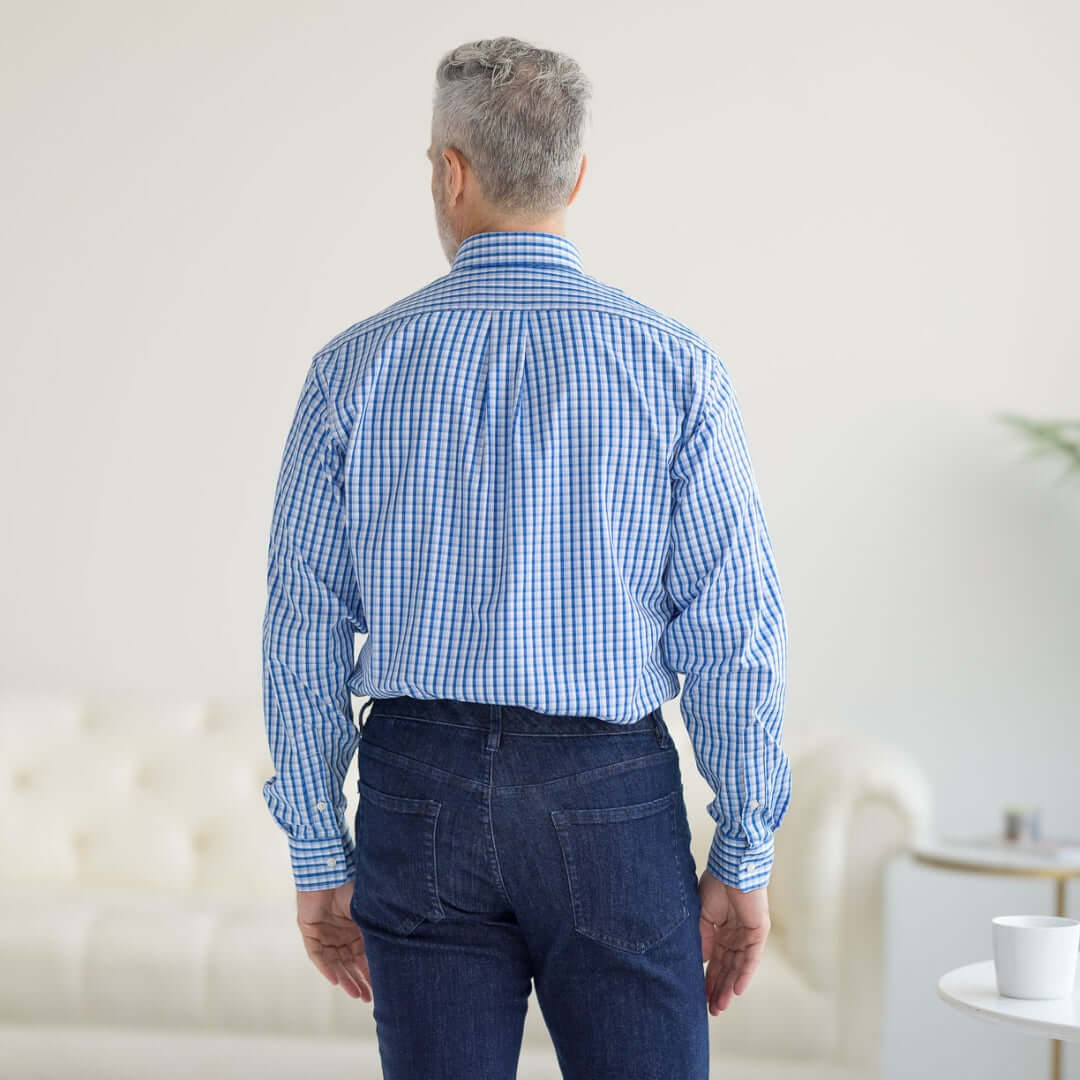 Back view of a man wearing a blue and white grid long sleeve button-down collar shirt with denim jeans.