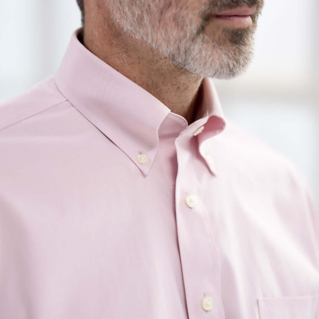 Close-up of a man wearing a Brooks Brothers pink polo with button-down collar and magnetic closures.
