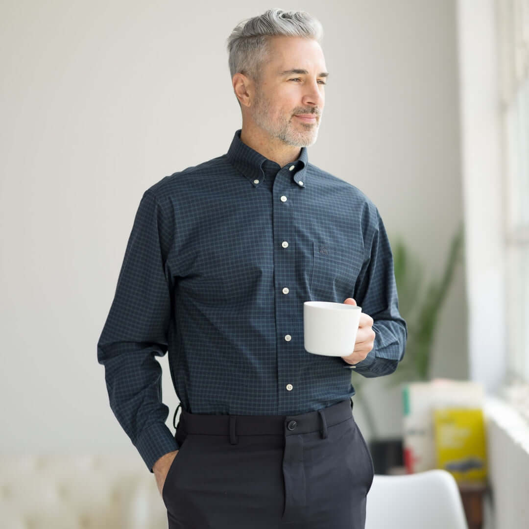 Man wearing Brooks Brothers x MagnaReady black watch button-down shirt, holding a cup, showcasing adaptive technology.