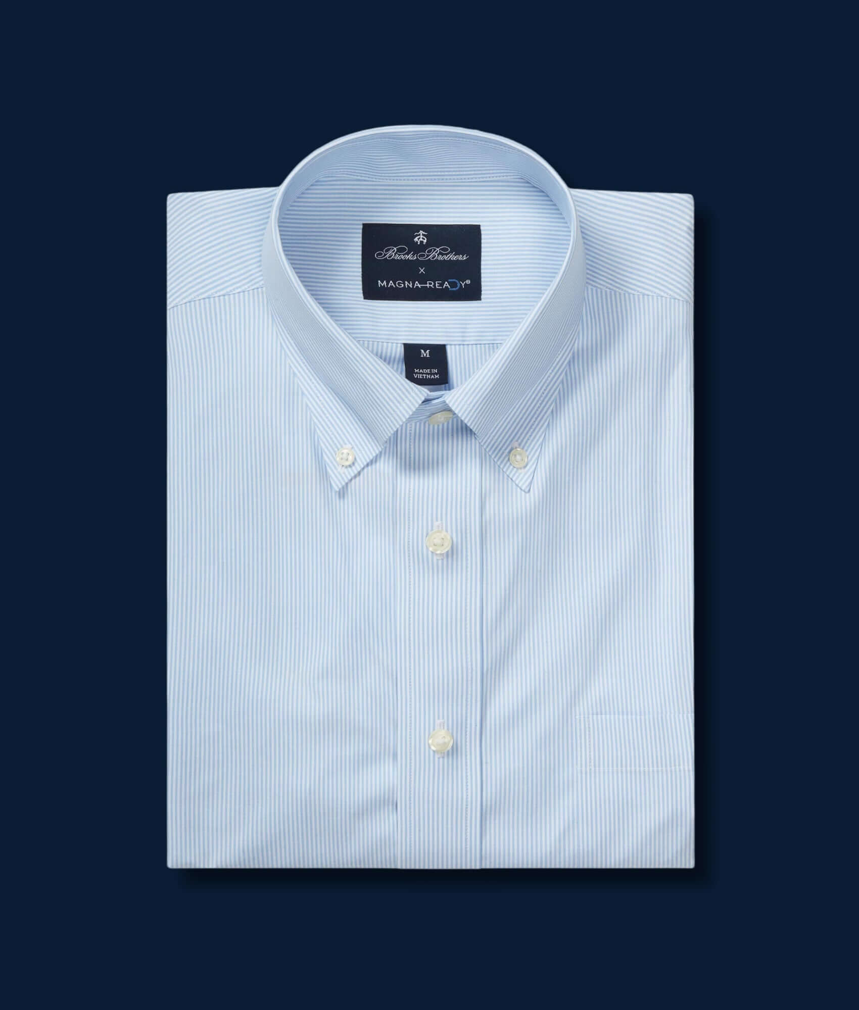 Brooks Brothers x MagnaReady blue and white stripe polo with button-down collar and magnetic closures, folded flat.
