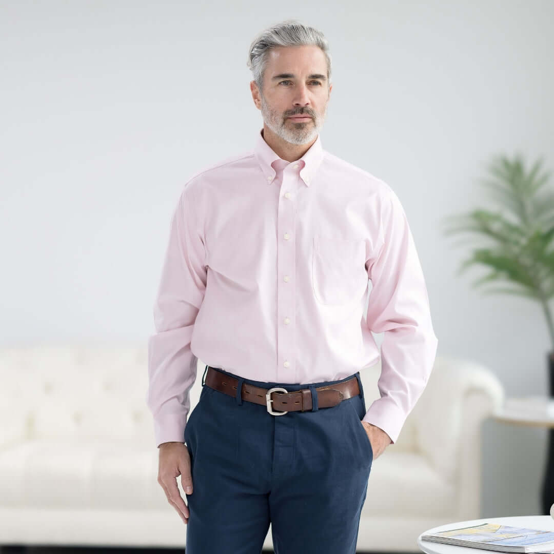 Man wearing Brooks Brothers x MagnaReady pink polo button-down shirt with magnetic closures, styled with navy pants.