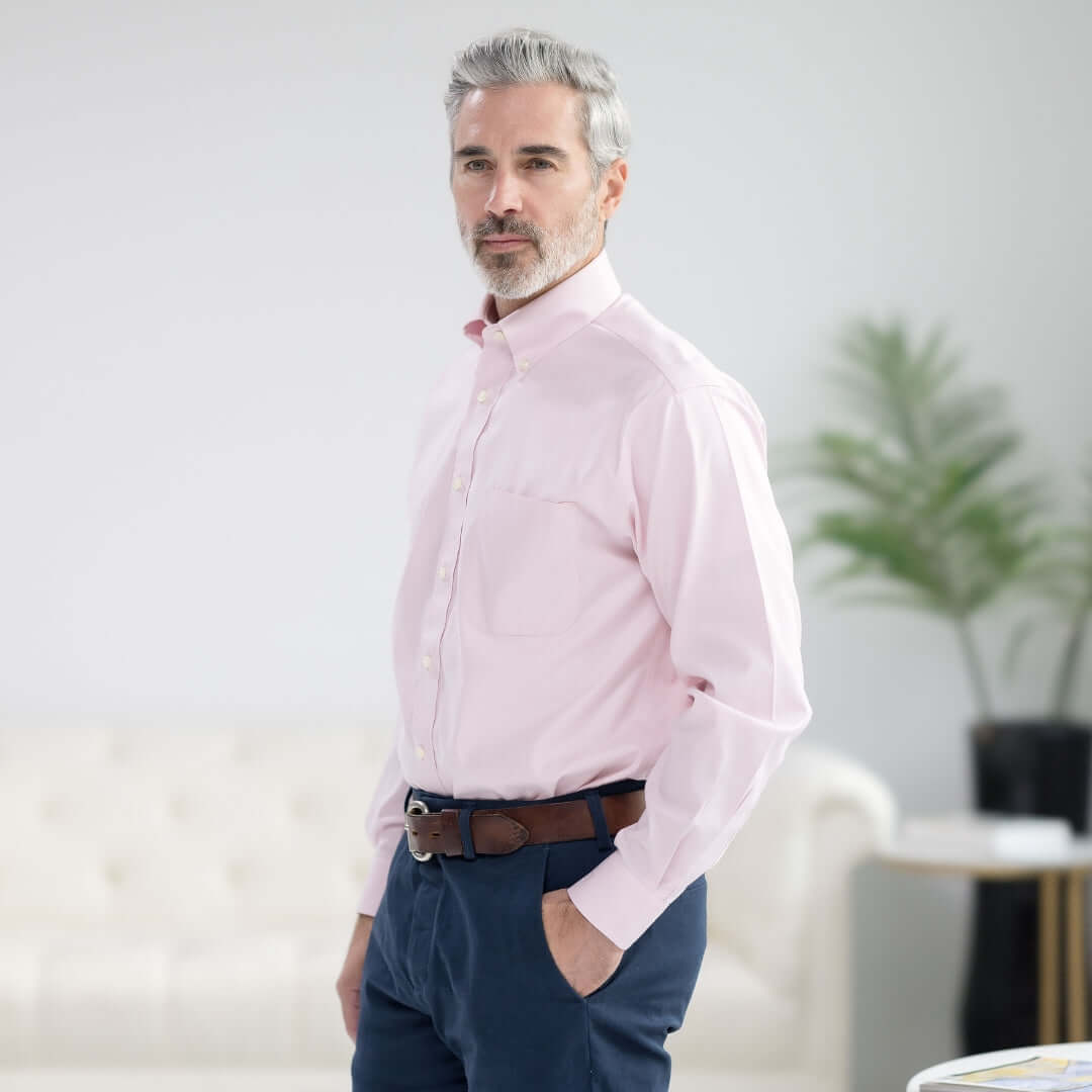 Model wearing Brooks Brothers x MagnaReady pink polo shirt with button-down collar and magnetic closures in a bright setting.