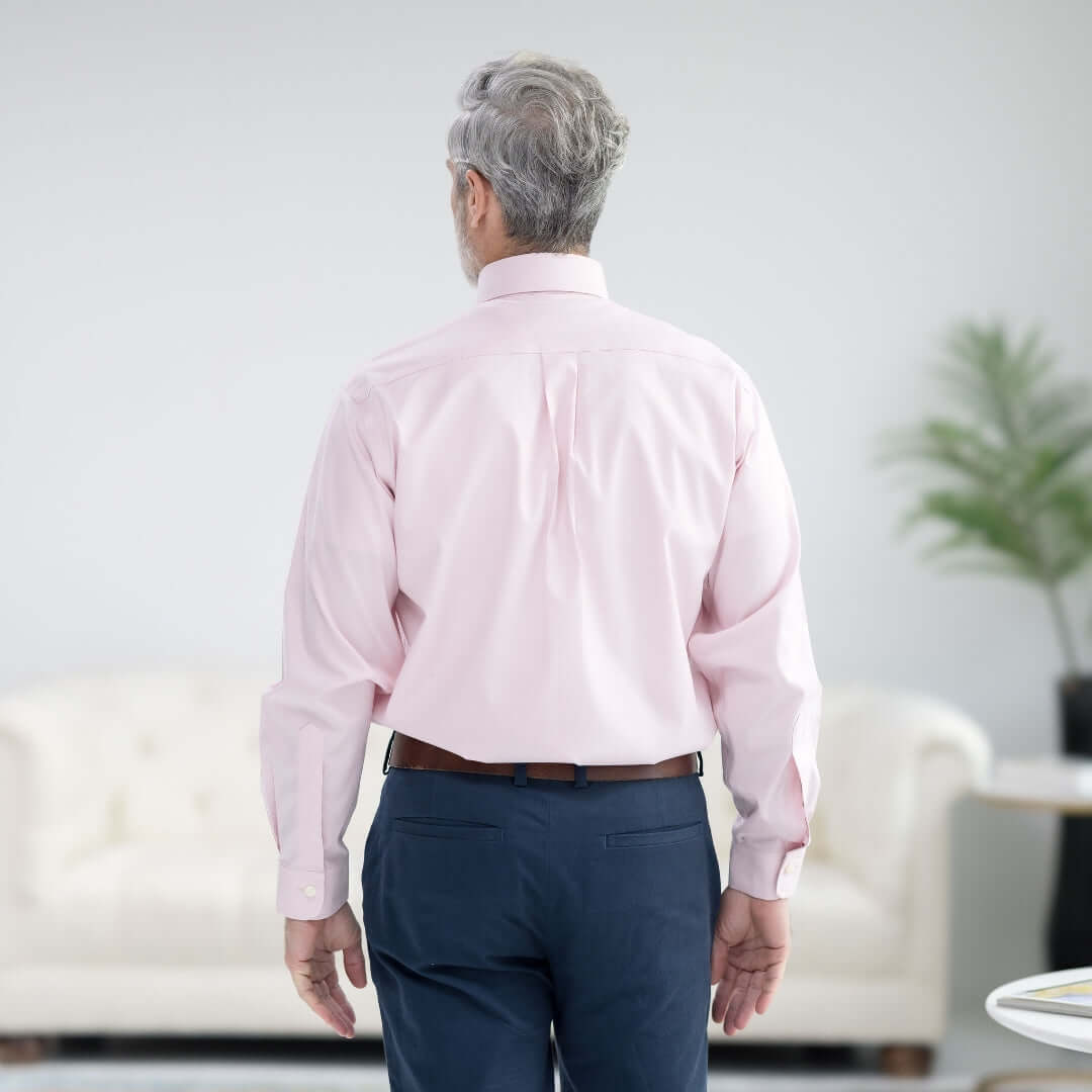 Back view of a man wearing a Brooks Brothers pink polo button-down shirt, showcasing its classic style and adaptive magnetic closures.