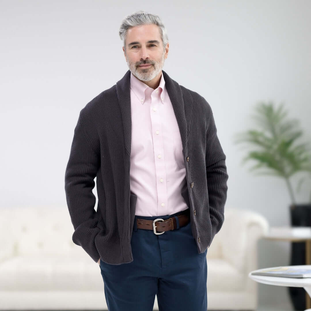 Man modeling a long sleeve pink polo shirt with button-down collar and magnetic closures, paired with a gray cardigan.