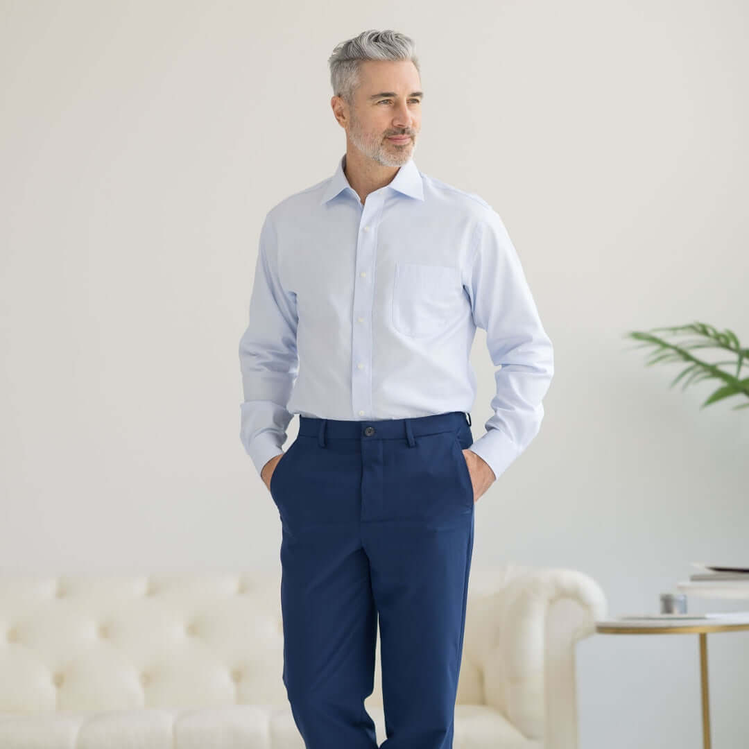 Man wearing a classic light blue 'Ryan' dress shirt with magnetic closures and navy dress pants, showcasing adaptive clothing.