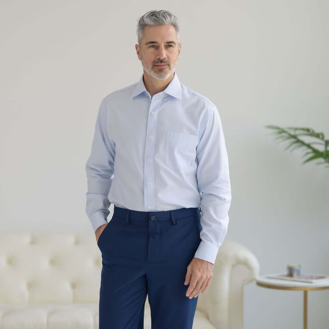 Man wearing a classic long sleeve light blue 'Ryan' dress shirt in a modern setting.