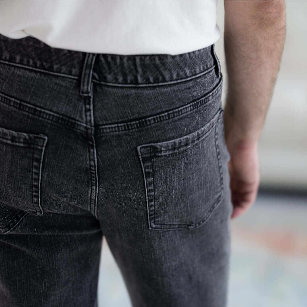 Back view of black wash five pocket jeans featuring a comfortable fit and adaptive magnetic fly design.
