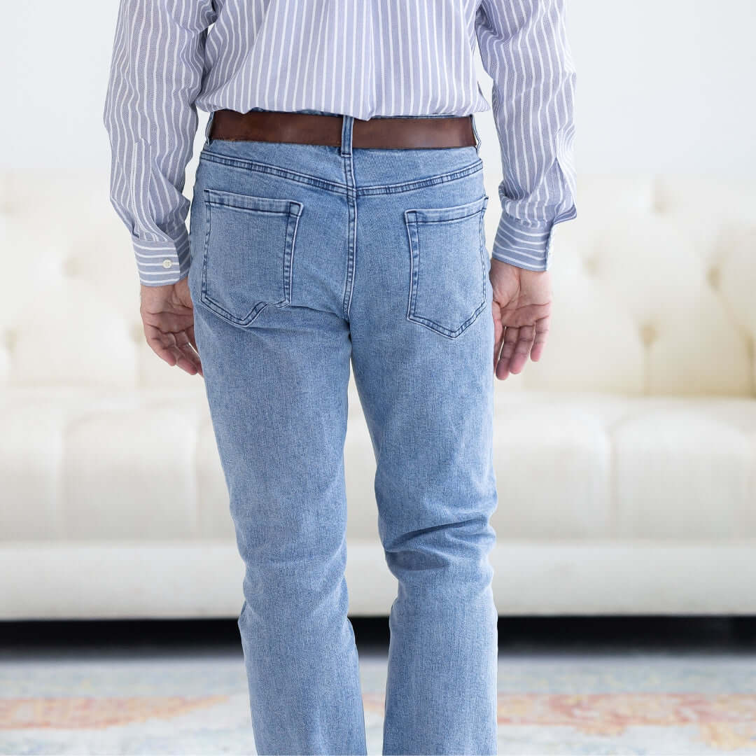 Rear view of man wearing light wash five pocket jeans with magnetic closures for adaptive dressing.
