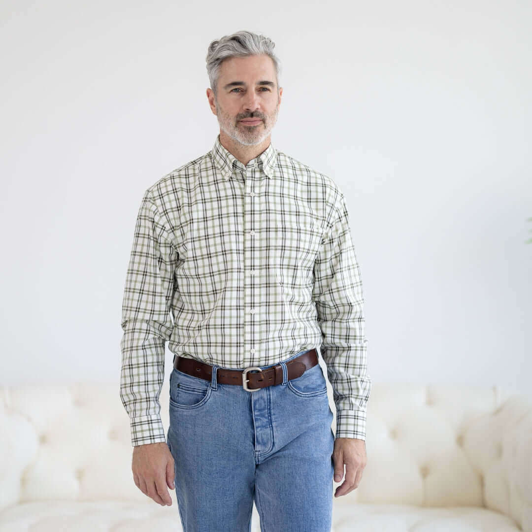 Man wearing a green and black plaid long sleeve button down shirt with hook and loop closures on a sofa.
