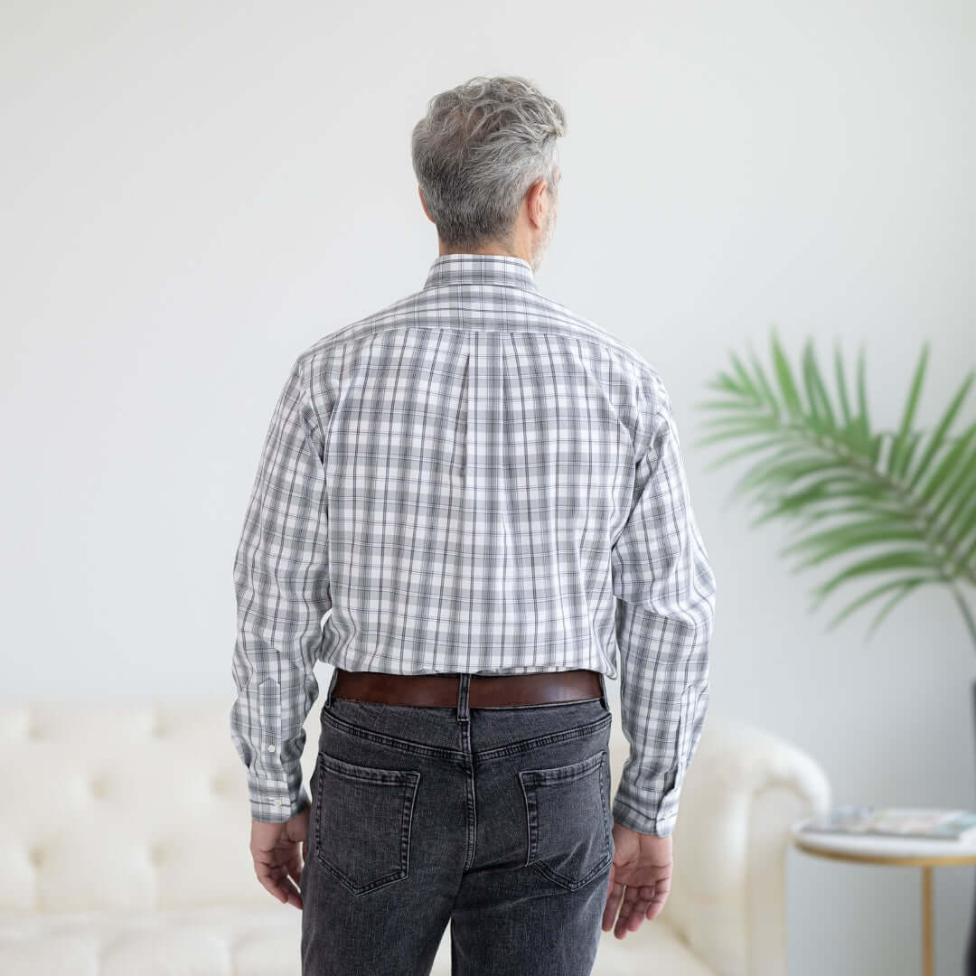 Back view of a man wearing a grey check long sleeve button down shirt with magnetic closures.