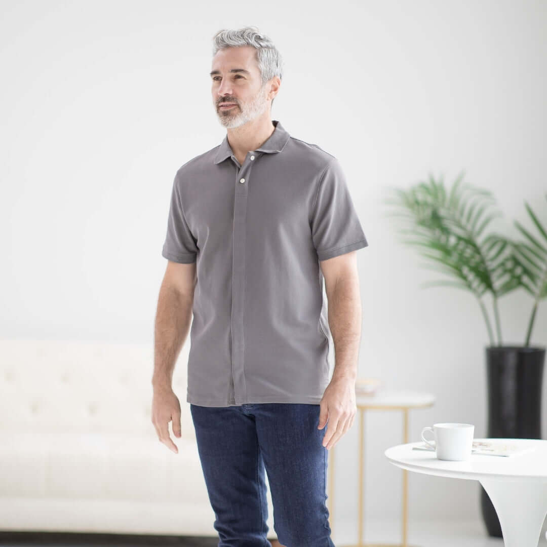 Man wearing a grey pique knit short sleeve polo shirt with magnetic closures, designed for comfort and accessibility.