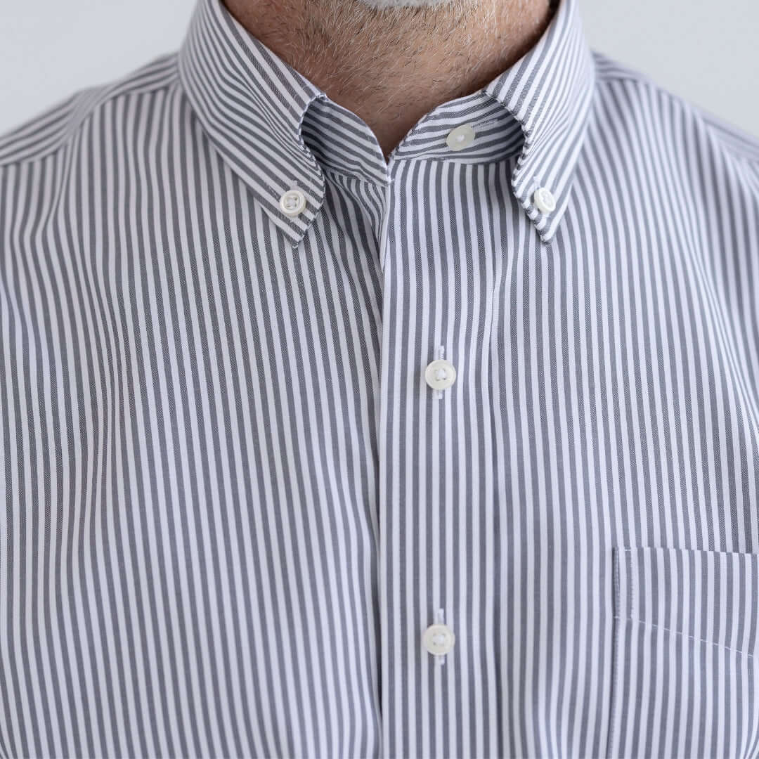 Close-up of a person wearing a striped shirt with a plain background