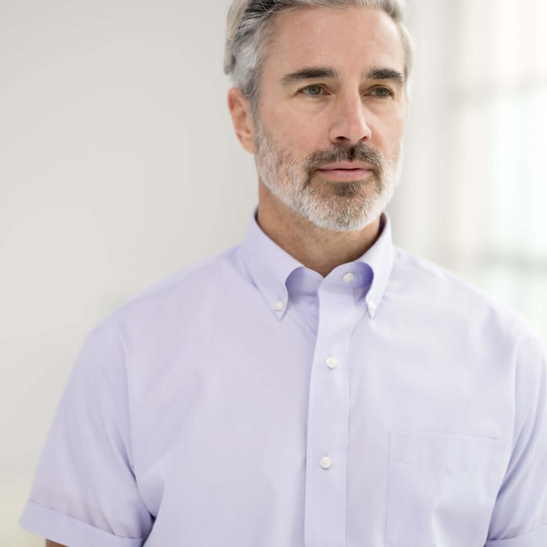 Man in lavender short sleeve button-down collar shirt, showcasing modern style and comfort.