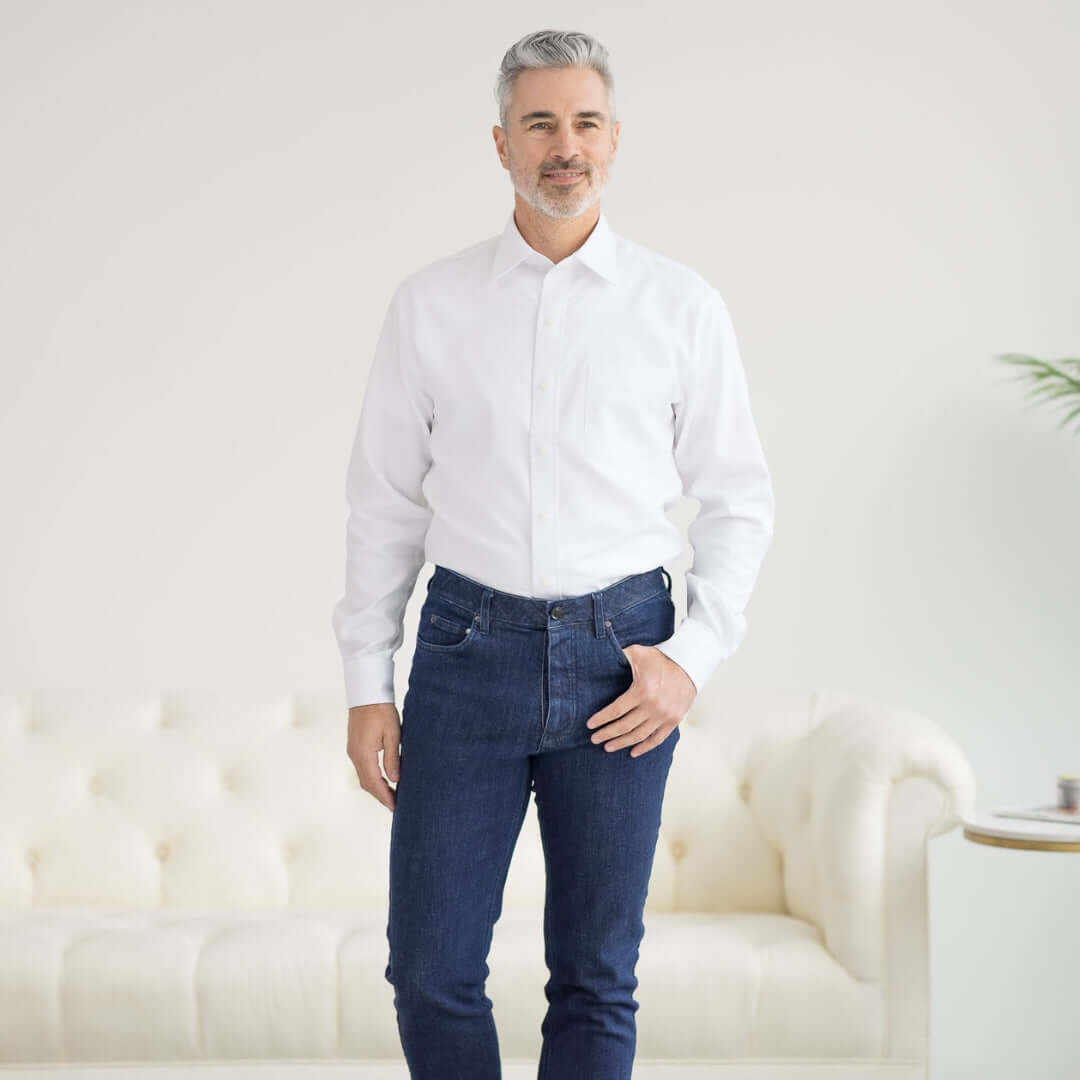 Man wearing a Long Sleeve White ‘Ryan’ Dress Shirt with Magnetic Closures, paired with jeans, in a modern living space.