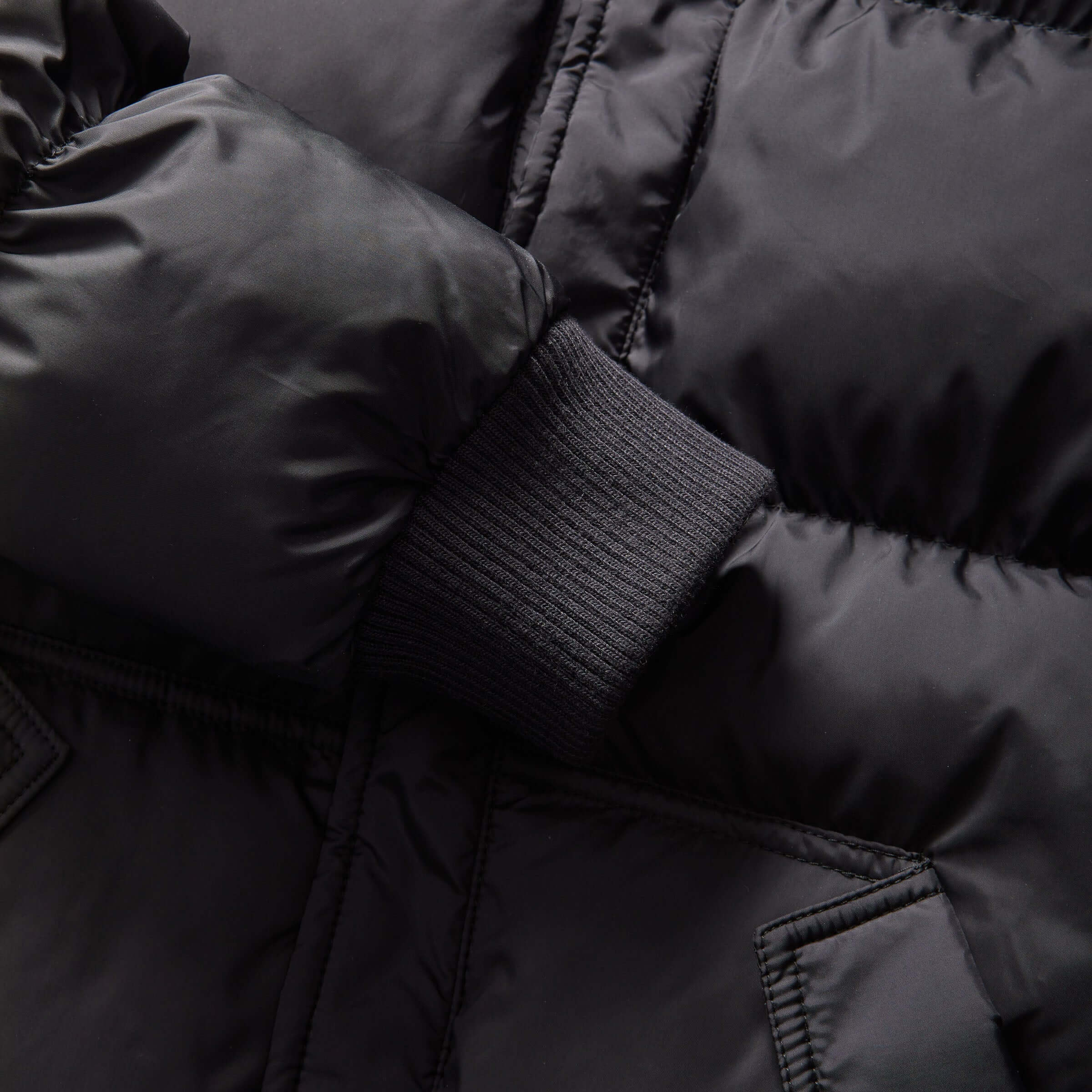 Close-up of the black MagnaMini kids puffer coat showing cozy material and elastic cuffs for warmth.