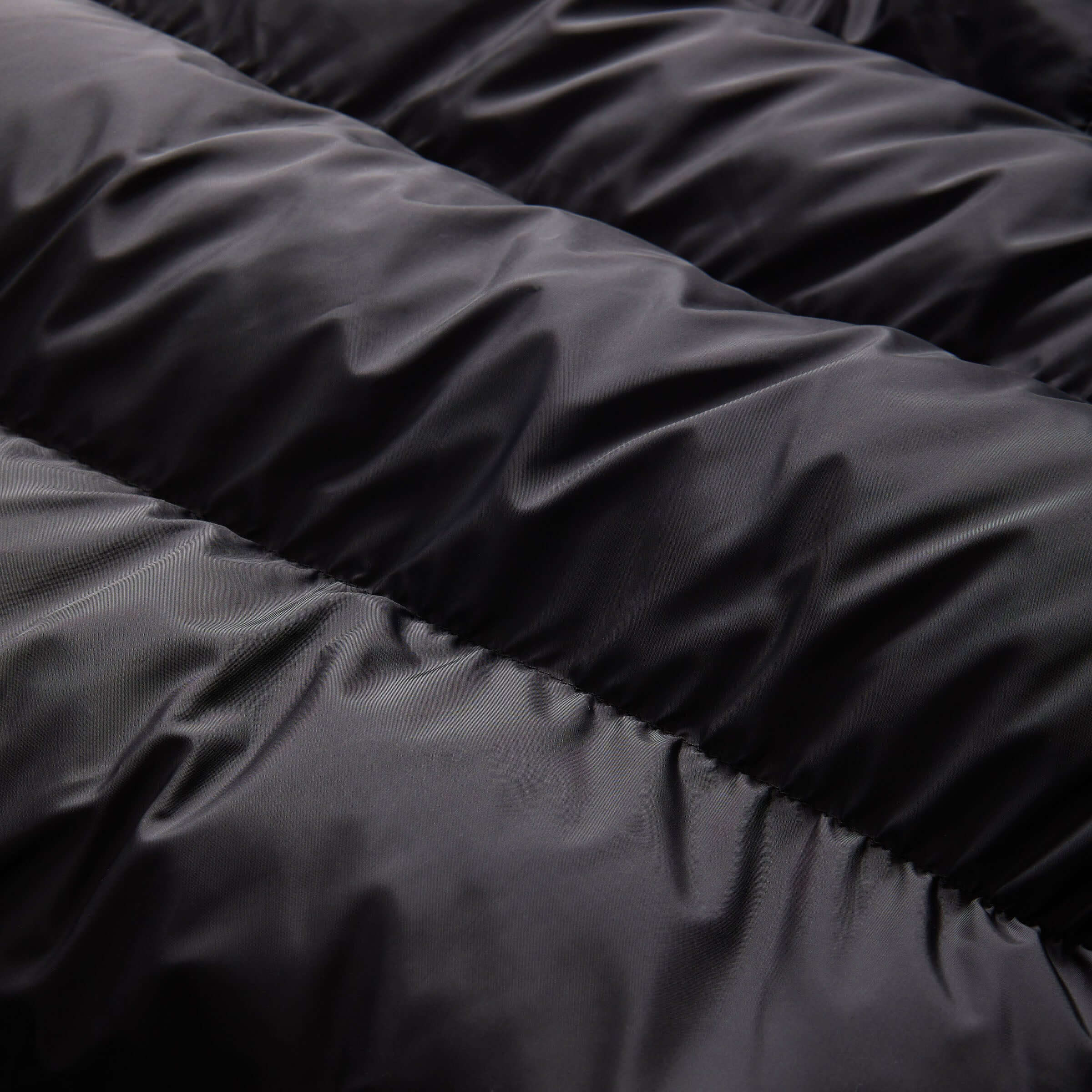 Close-up of the luxurious black fabric texture of the MagnaMini Kids waterproof puffer coat.