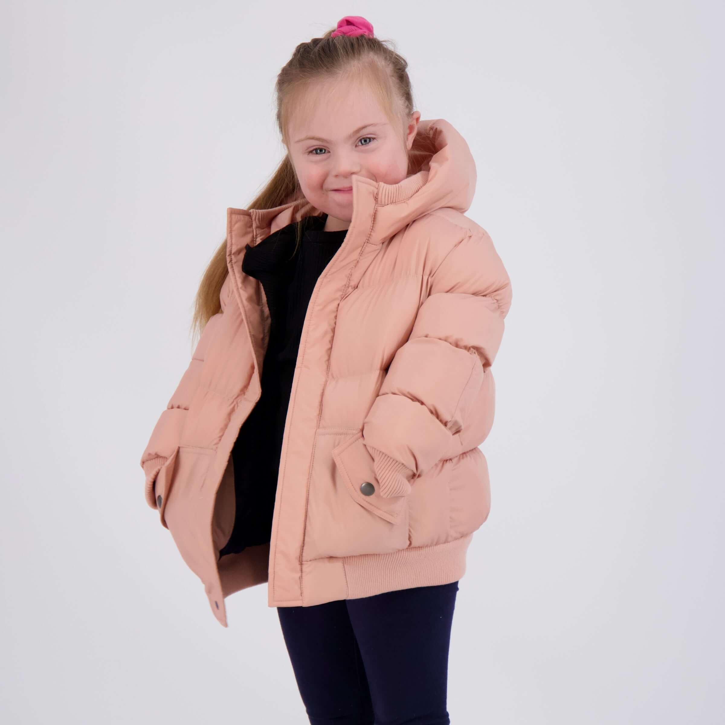 Girl wearing a pink MagnaMini kids magnetic water-resistant puffer coat with hood, smiling confidently.