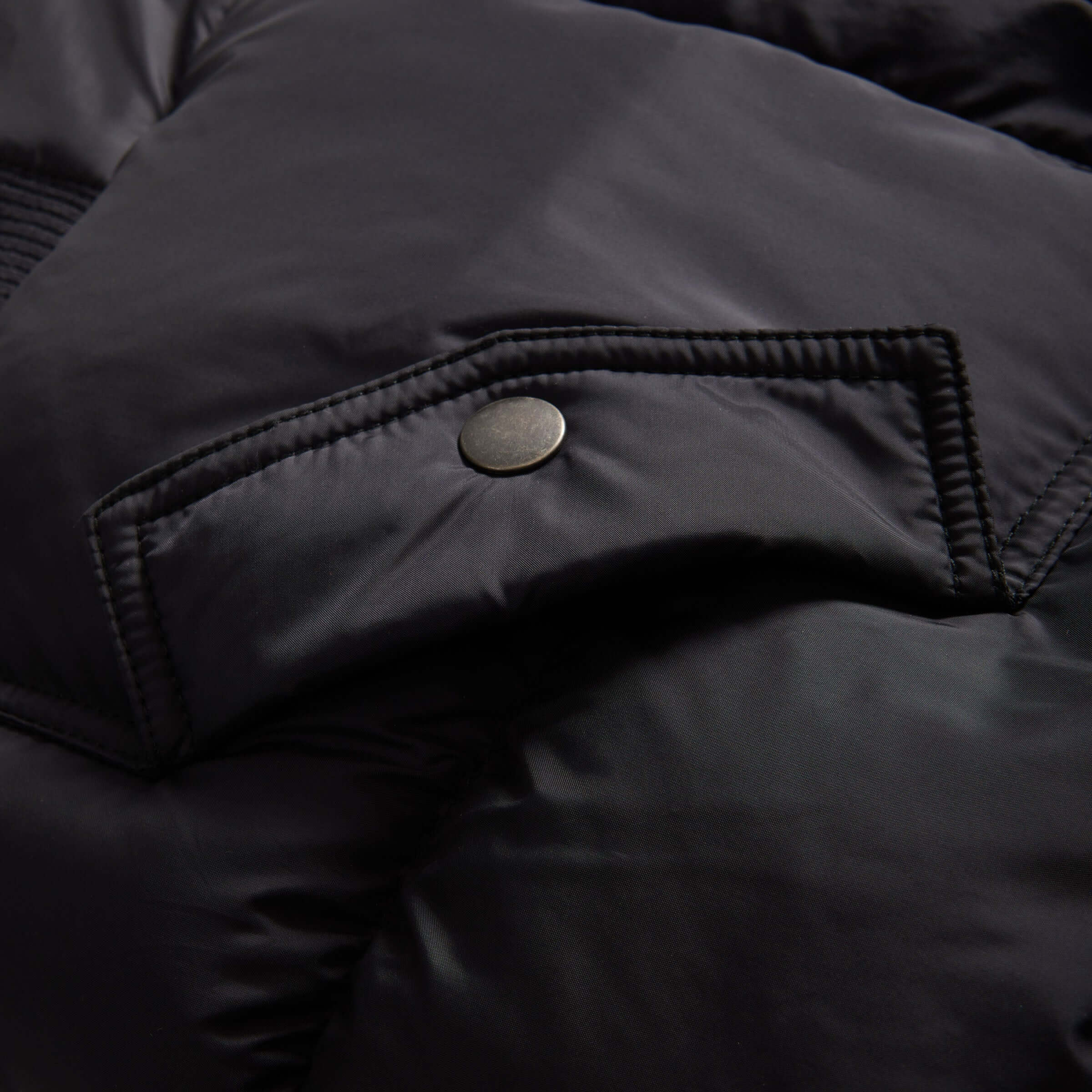 Close-up of the black puffer coat showing the magnetic closure and soft quilted fabric.