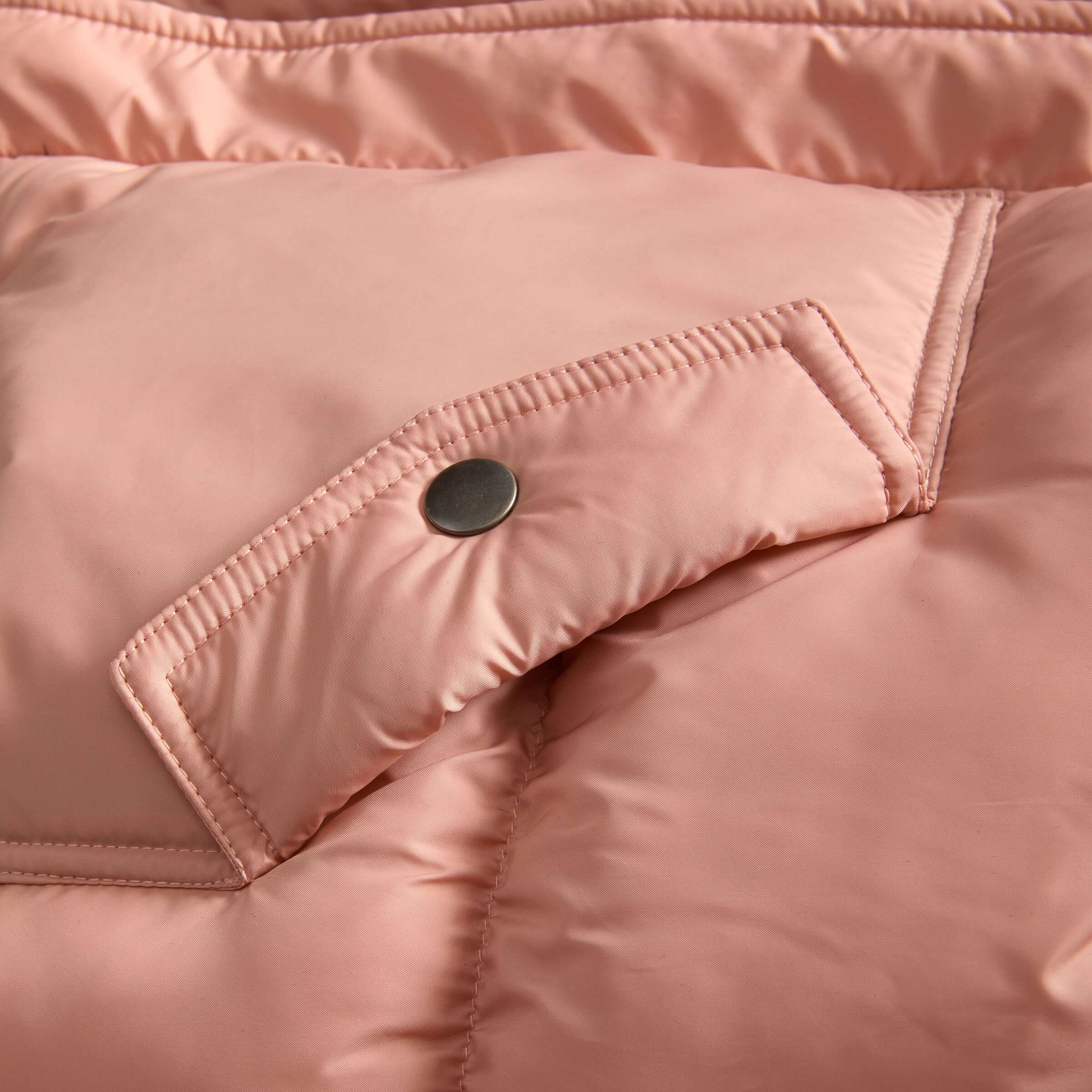 Close-up of the pink MagnaMini kids puffer coat showing the water-resistant fabric and snap closure detail.