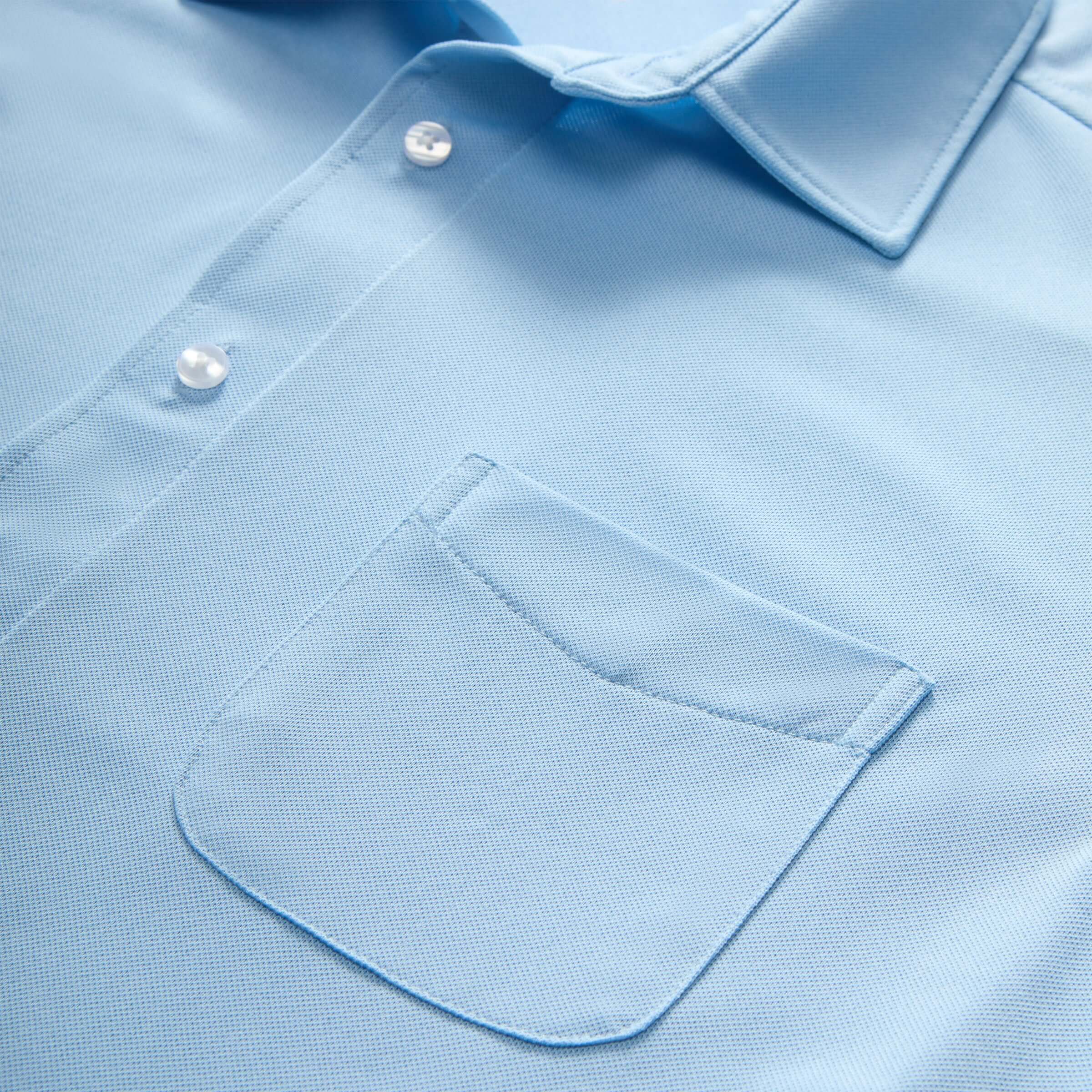 Close-up of a light blue shirt featuring a pocket and classic buttons for a stylish look.