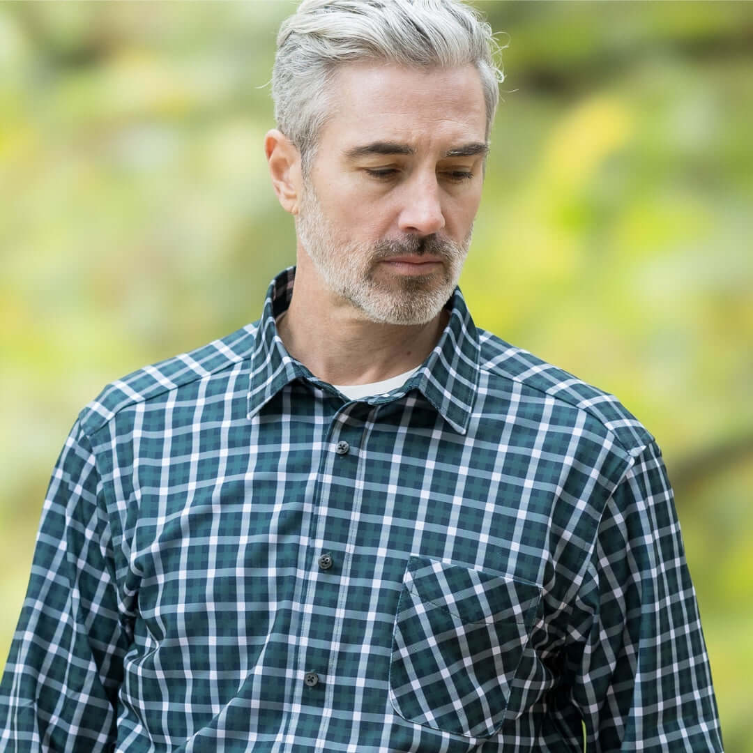 Man wearing a green plaid MagnaReady long sleeve shirt outdoors, showcasing comfort and style.