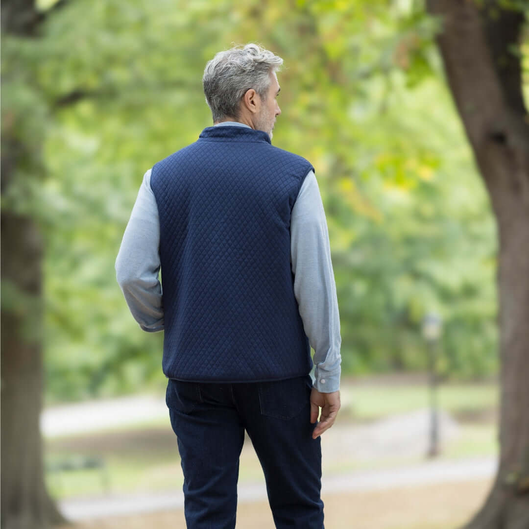 Man wearing a navy MagnaReady® reversible diamond quilted vest outdoors in a park.