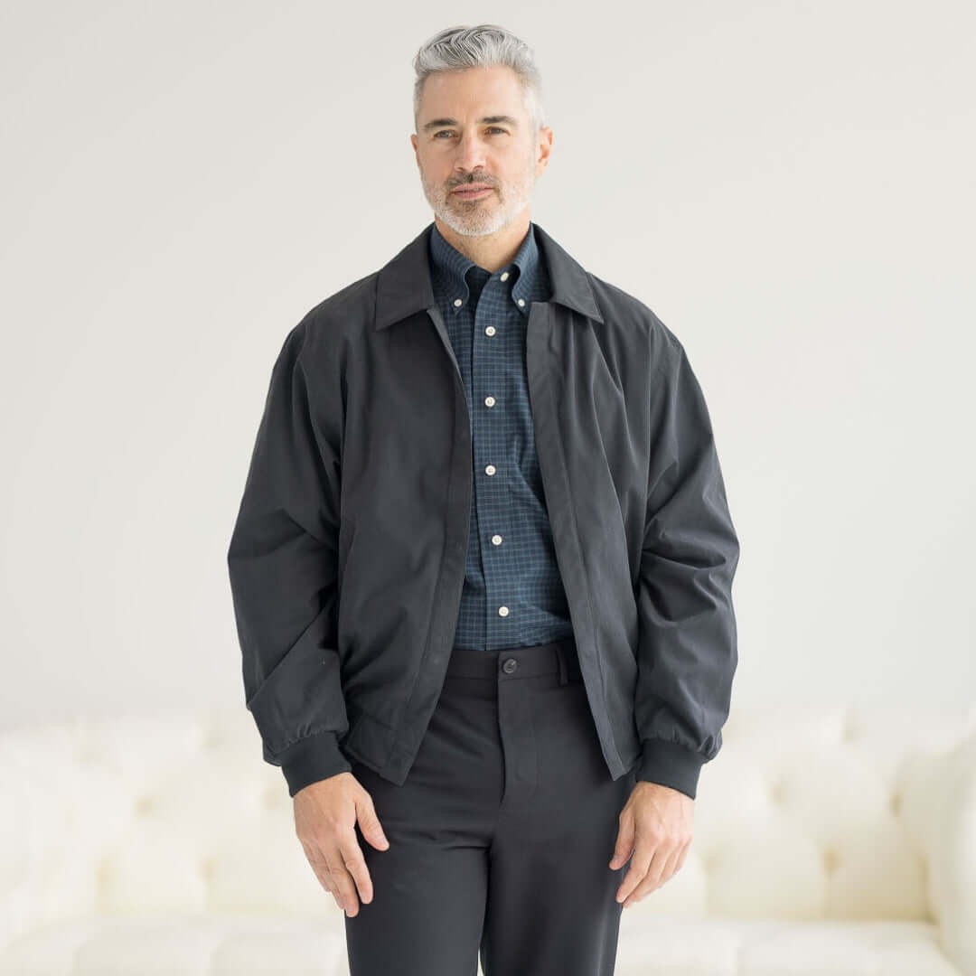 A man wearing a MagnaReady® X Weatherproof Black Golf Jacket, showcasing modern style and magnetic closures.